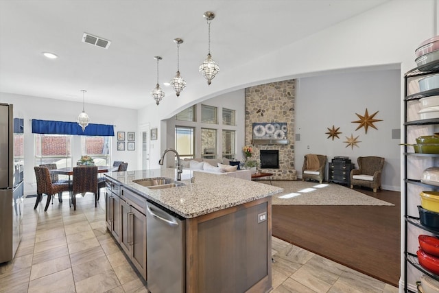 1608 Nighthawk Ln, Mansfield, TX 76063 - kitchen with dishwasher, a sink, light stone countertops, a stone fireplace, and an island with sink