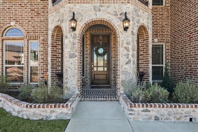 view of exterior entry with brick siding and stone siding