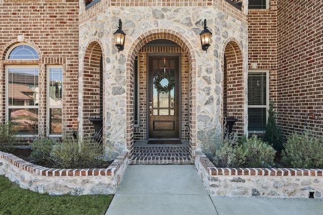 view of exterior entry featuring brick siding and stone siding
