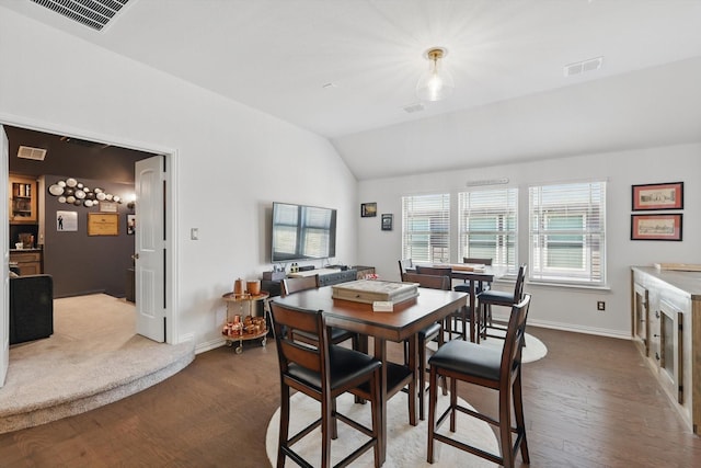 dining area with visible vents, baseboards, lofted ceiling, and wood finished floors