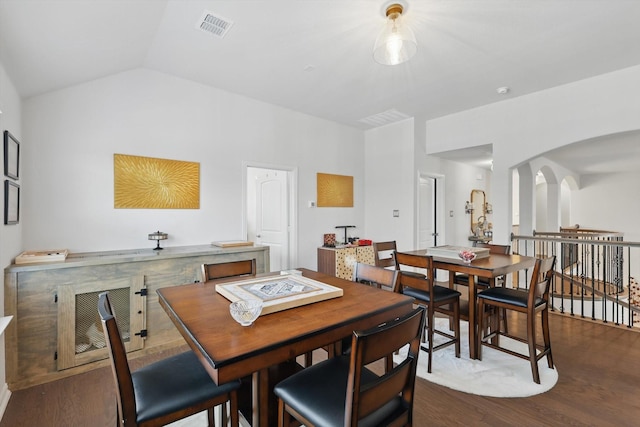 dining area featuring vaulted ceiling, arched walkways, visible vents, and dark wood-style flooring