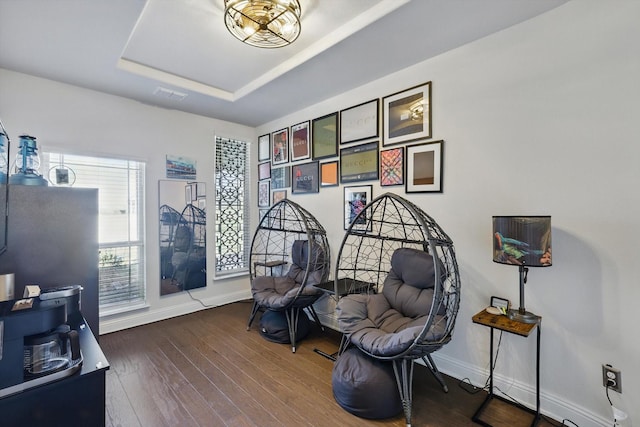 sitting room featuring visible vents, baseboards, a tray ceiling, and hardwood / wood-style flooring