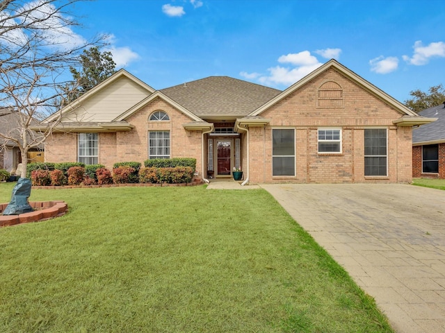 ranch-style home with brick siding, a front lawn, and roof with shingles