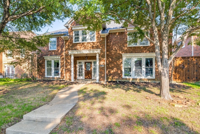 view of front of property with fence, a front lawn, and brick siding