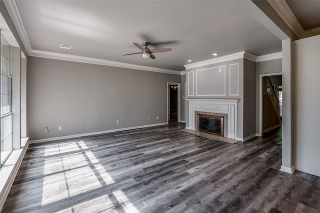 unfurnished living room featuring dark wood-type flooring, a premium fireplace, visible vents, baseboards, and crown molding