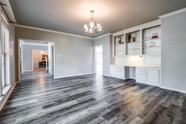 interior space featuring a chandelier, built in desk, dark wood-type flooring, and crown molding