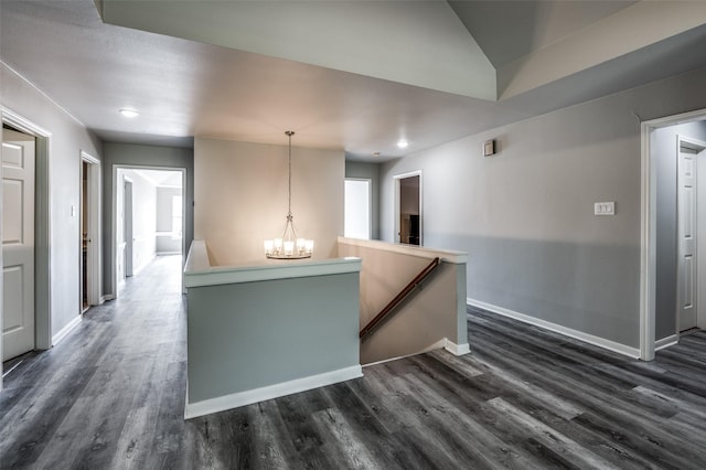 corridor featuring baseboards, a chandelier, dark wood finished floors, and an upstairs landing