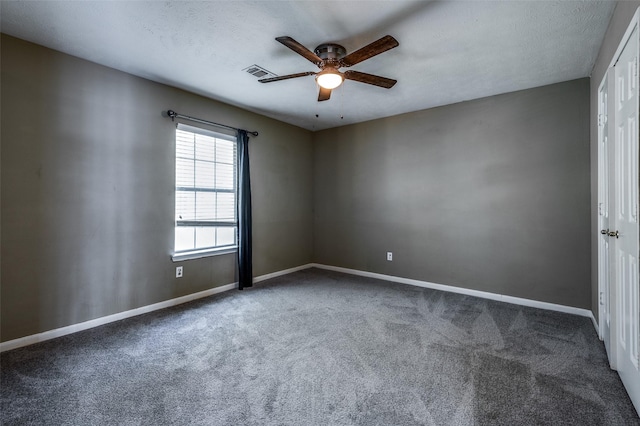 carpeted spare room with ceiling fan, a textured ceiling, visible vents, and baseboards