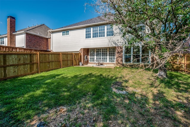 back of property with brick siding, a lawn, and a fenced backyard