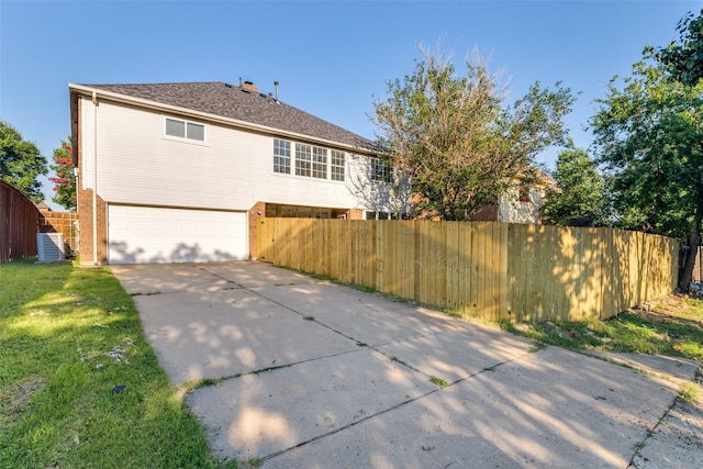 back of house featuring brick siding, a yard, concrete driveway, fence, and a garage