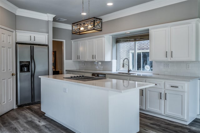 kitchen with a center island, visible vents, ornamental molding, a sink, and stainless steel fridge