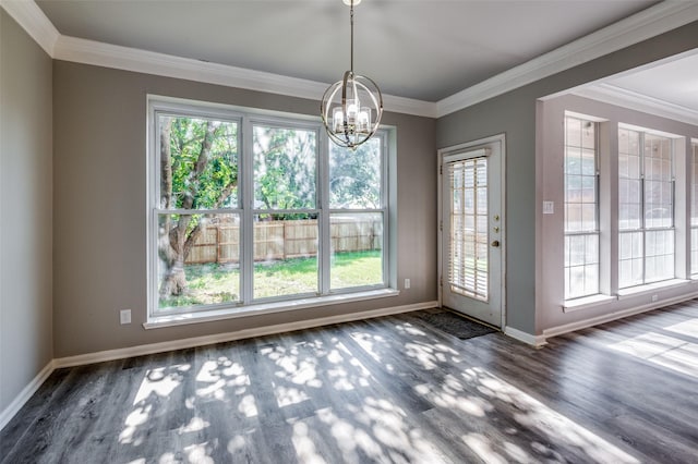 unfurnished dining area featuring baseboards, ornamental molding, wood finished floors, and a notable chandelier