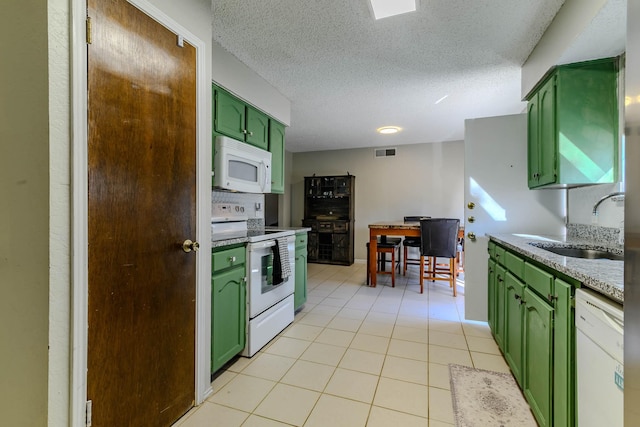 kitchen featuring light tile patterned floors, white appliances, a sink, visible vents, and green cabinetry