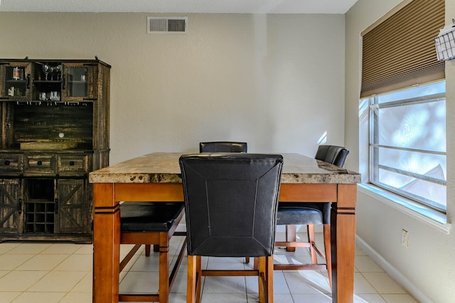 dining space featuring baseboards, visible vents, and light tile patterned flooring