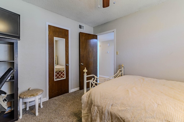 bedroom with a textured ceiling, ceiling fan, carpet floors, visible vents, and baseboards