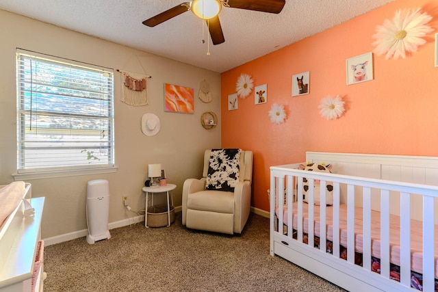 bedroom featuring baseboards, carpet flooring, a crib, and a textured ceiling