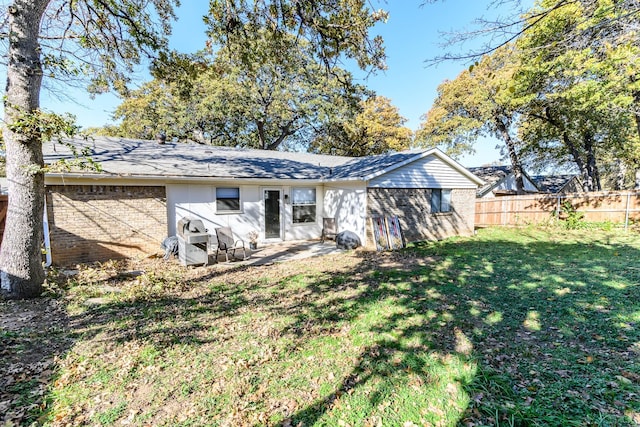 rear view of house with brick siding, a lawn, and fence