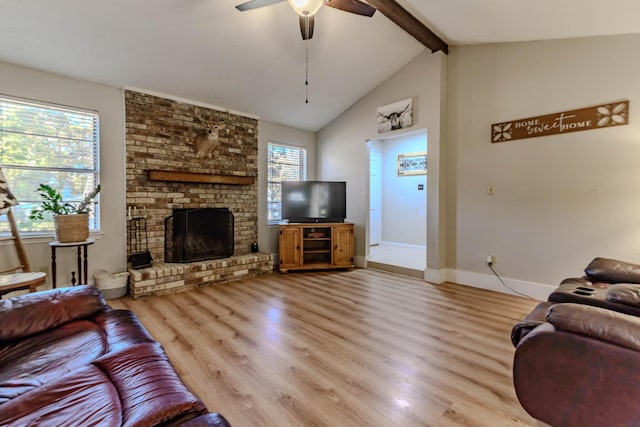 living area featuring lofted ceiling with beams, ceiling fan, a fireplace, wood finished floors, and baseboards