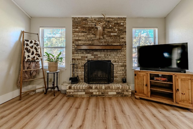 living area with a healthy amount of sunlight, a fireplace, and light wood-style flooring