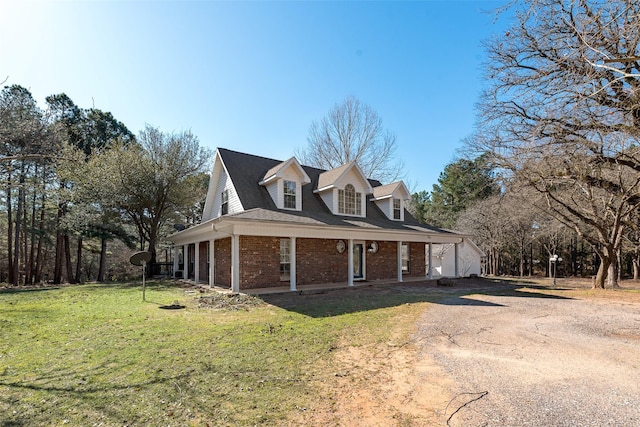 view of front of property with dirt driveway, brick siding, a front yard, and covered porch