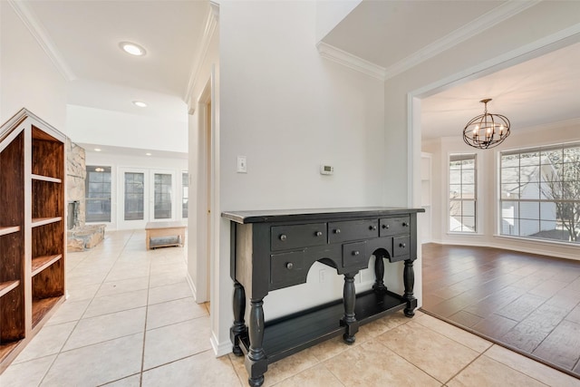 hallway featuring light tile patterned floors, baseboards, ornamental molding, and an inviting chandelier