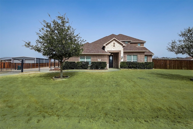 view of front facade with brick siding, fence, and a front yard