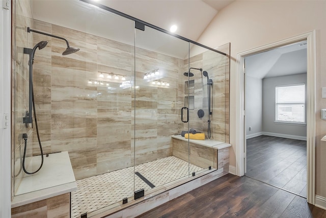 full bathroom with vaulted ceiling, a stall shower, wood finished floors, and baseboards