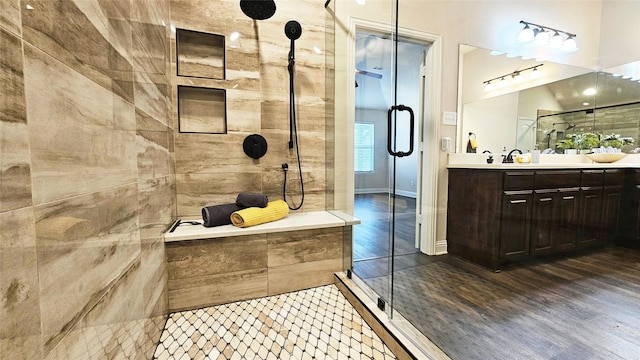 bathroom with tiled shower, wood finished floors, and vanity