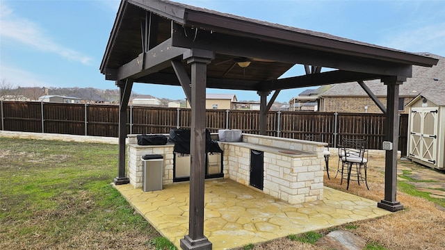 view of patio with a fenced backyard, a storage shed, a gazebo, and area for grilling