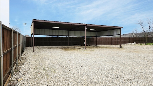 view of vehicle parking featuring driveway, fence, and a carport