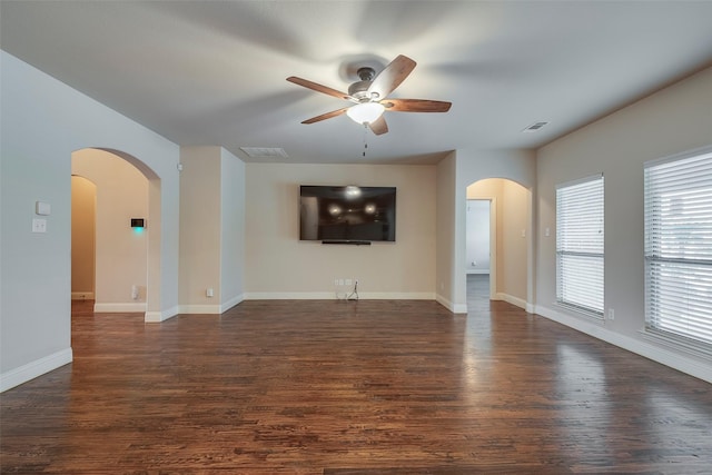 unfurnished living room featuring visible vents, arched walkways, dark wood finished floors, and baseboards