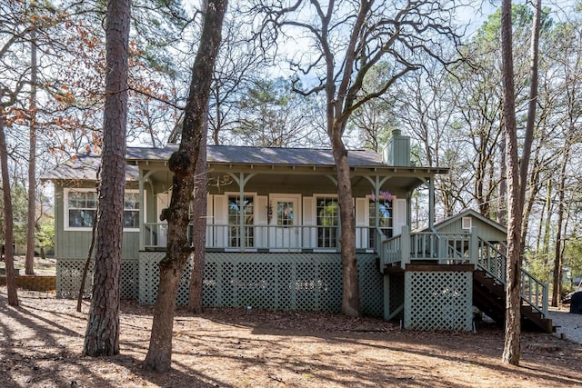 view of front of home featuring roof with shingles, a porch, stairway, and a chimney