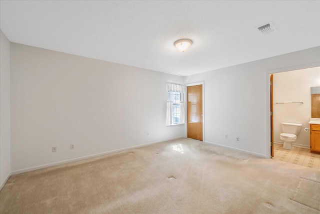 unfurnished bedroom with ensuite bathroom, baseboards, visible vents, and light colored carpet