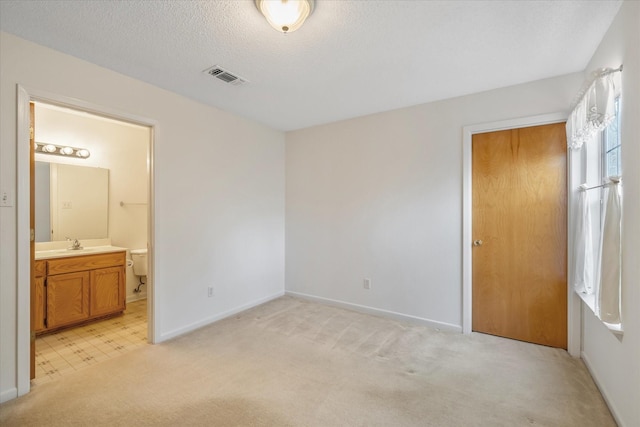 2682 Holly Trl E, Holly Lake Ranch, TX 75765 - unfurnished bedroom with light carpet, baseboards, a sink, connected bathroom, and a textured ceiling