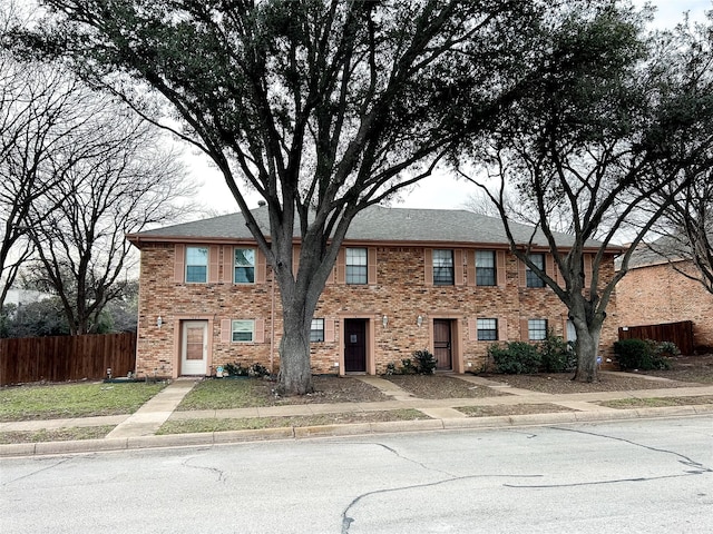 view of front of property with brick siding and fence