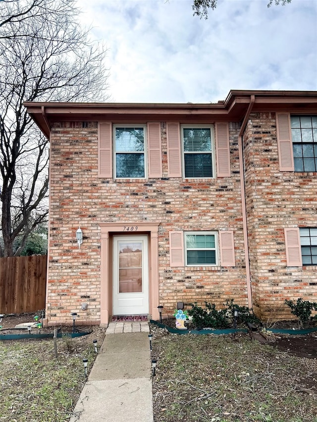 view of front of property featuring brick siding and fence