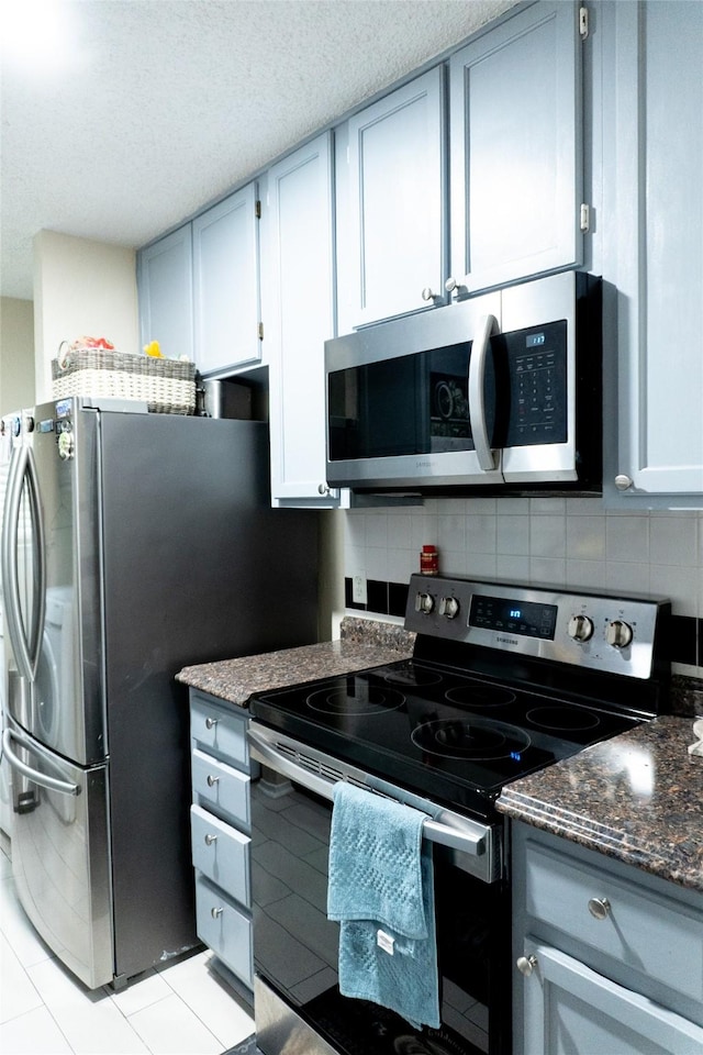 7409 Kingswood Dr, Fort Worth, TX 76133 - kitchen with appliances with stainless steel finishes, a textured ceiling, dark stone countertops, and tasteful backsplash