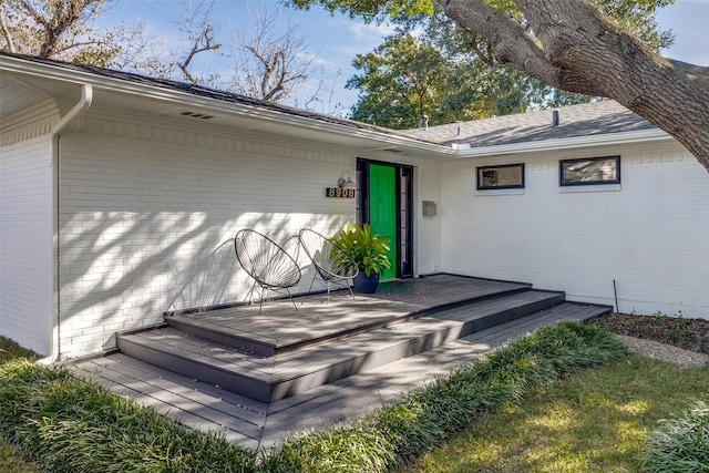 entrance to property with a deck and brick siding