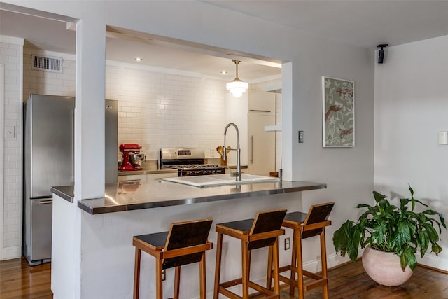 kitchen featuring appliances with stainless steel finishes, dark wood finished floors, backsplash, and a kitchen breakfast bar