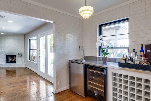 bar with hardwood / wood-style flooring, beverage cooler, a fireplace, freestanding refrigerator, and a dry bar