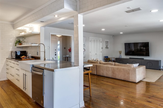 kitchen with visible vents, a breakfast bar, hardwood / wood-style floors, open shelves, and a sink