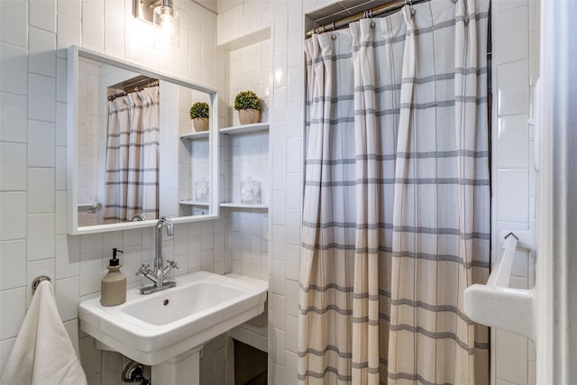 bathroom with curtained shower, tile walls, backsplash, and a sink