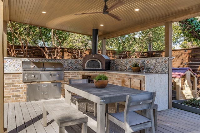 wooden deck with area for grilling, ceiling fan, fence, outdoor dining area, and a sink