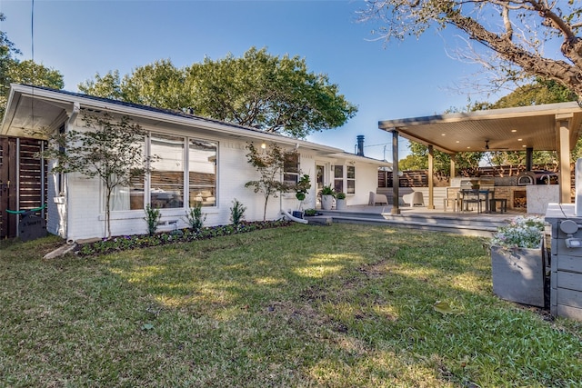 back of house with a patio area, brick siding, and a lawn