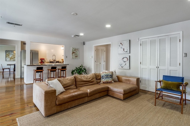 living area with recessed lighting, wood-type flooring, visible vents, and baseboards