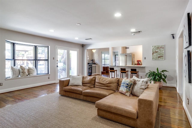 living area featuring recessed lighting, wood-type flooring, visible vents, and baseboards