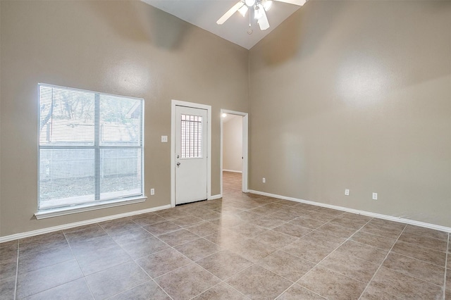 spare room with light tile patterned floors, ceiling fan, high vaulted ceiling, and baseboards