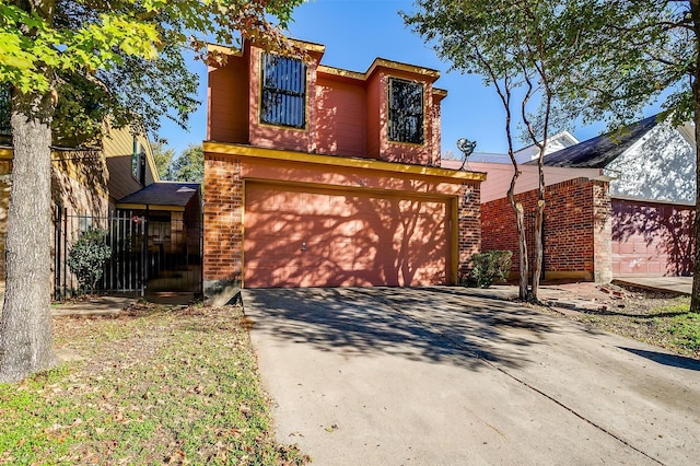 traditional-style home featuring an attached garage, concrete driveway, and brick siding