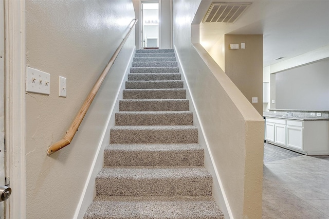 staircase with visible vents and a textured wall