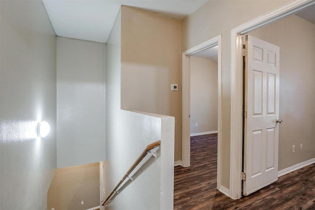 hall featuring baseboards, wood finished floors, and an upstairs landing